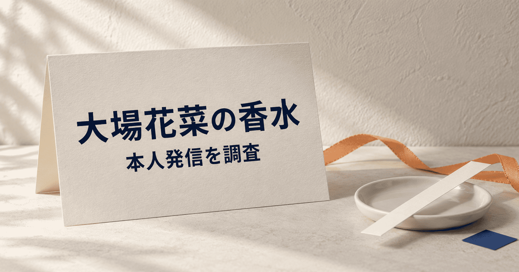 「大場花菜の香水 本人発信を調査」と印刷したカードとオレンジのリボンの静物イメージ