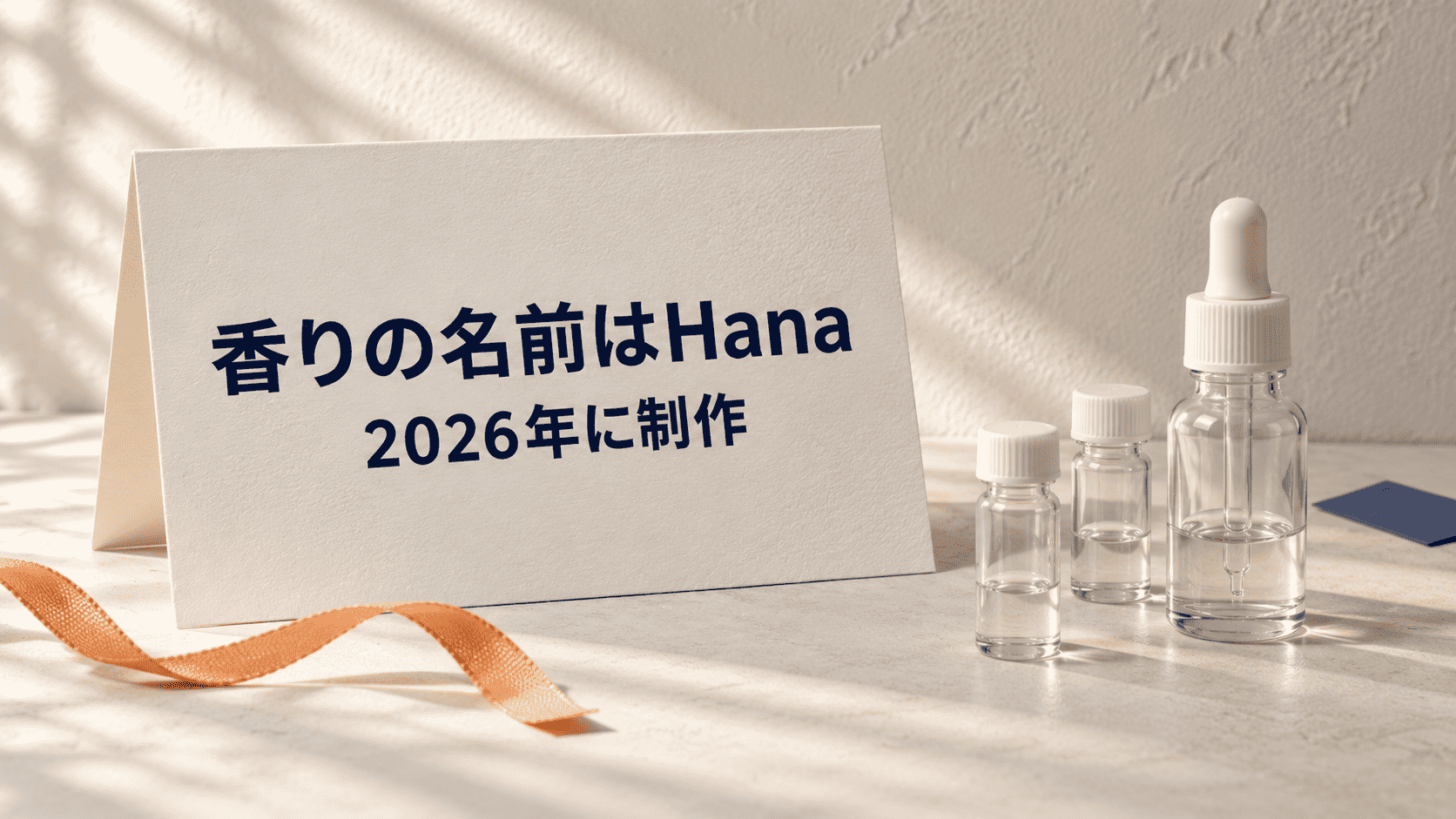 「香りの名前はHana 2026年に制作」と印刷したカードと無地の調香用ガラス器具の静物イメージ